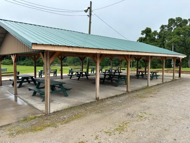 Open-air covered pavilion with green picnic tables at the Izaak Walton League grounds